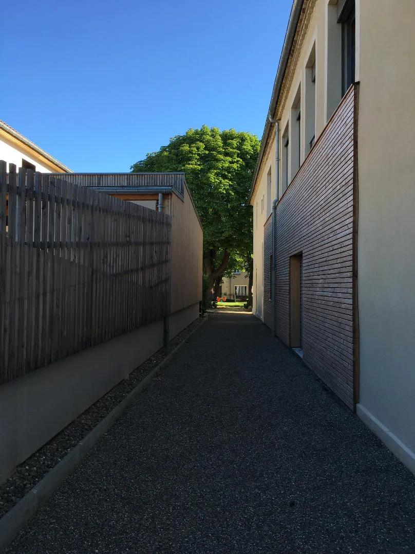 Réalisation d’une crèche en ossature bois à Vic-Fezensac, allée entre deux bâtiments avec finitions en bois